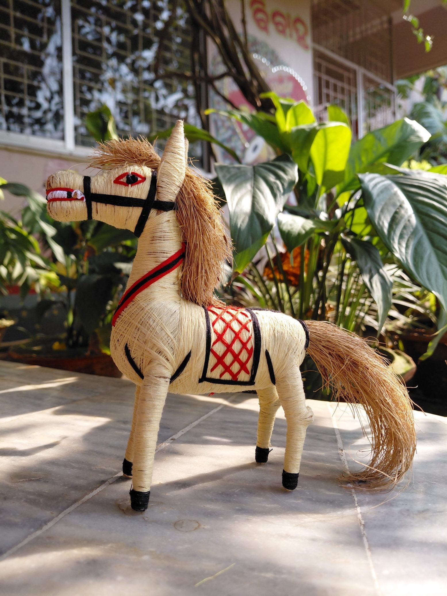 Handcrafted coir horse figurine made from natural coconut fibres with decorative saddle, natural fibre mane, and tail.